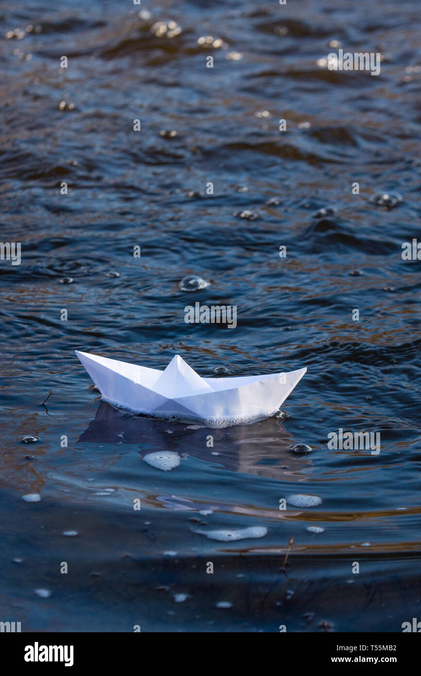 Ein Papier Boot auf eine turbulente Strom von Wasser kämpft mit der Strömung. Kleines Papier Boot fließt entlang des Flusses Stockfoto