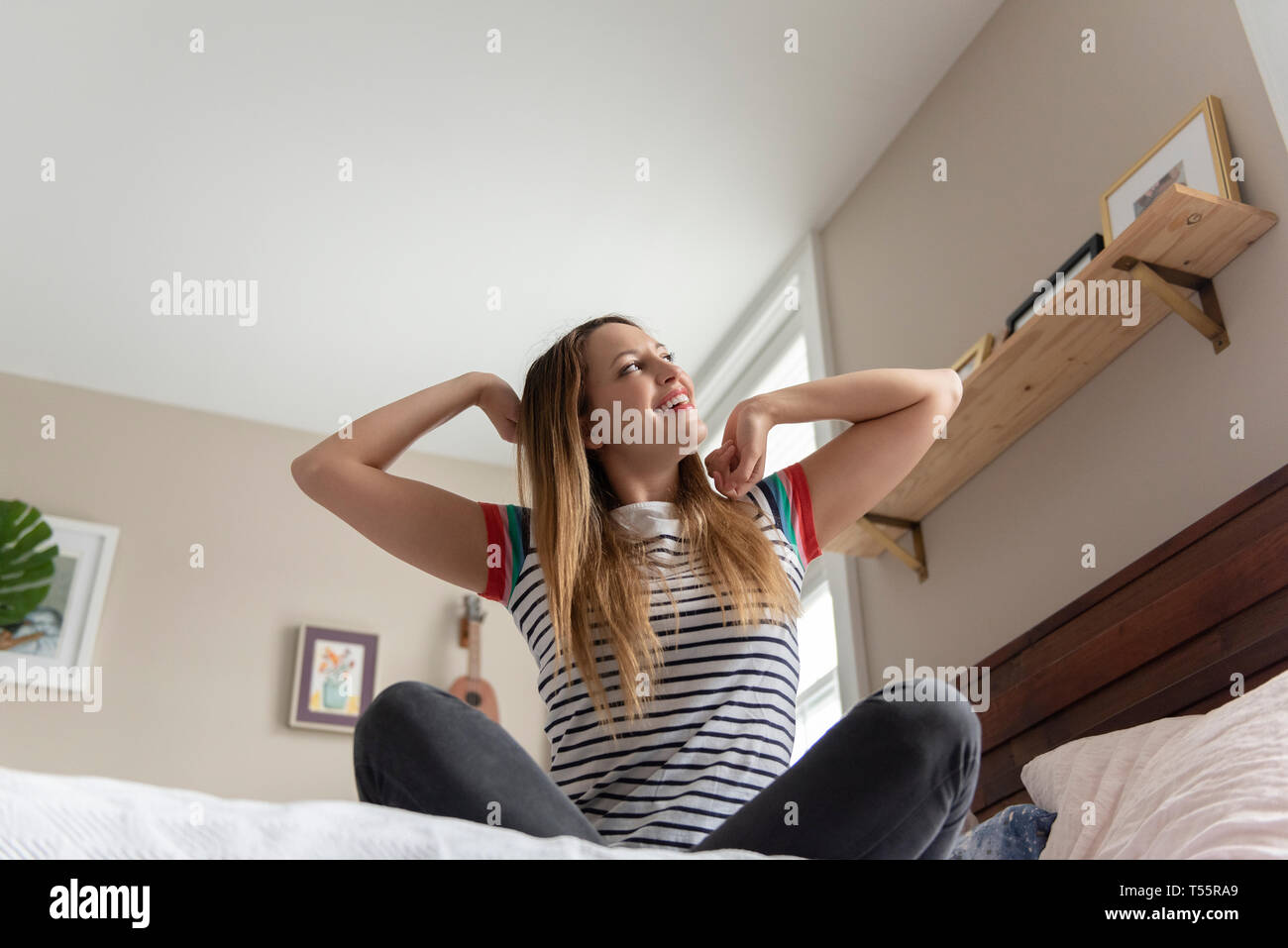 Junge Frau, die Dehnung auf Bett Stockfoto