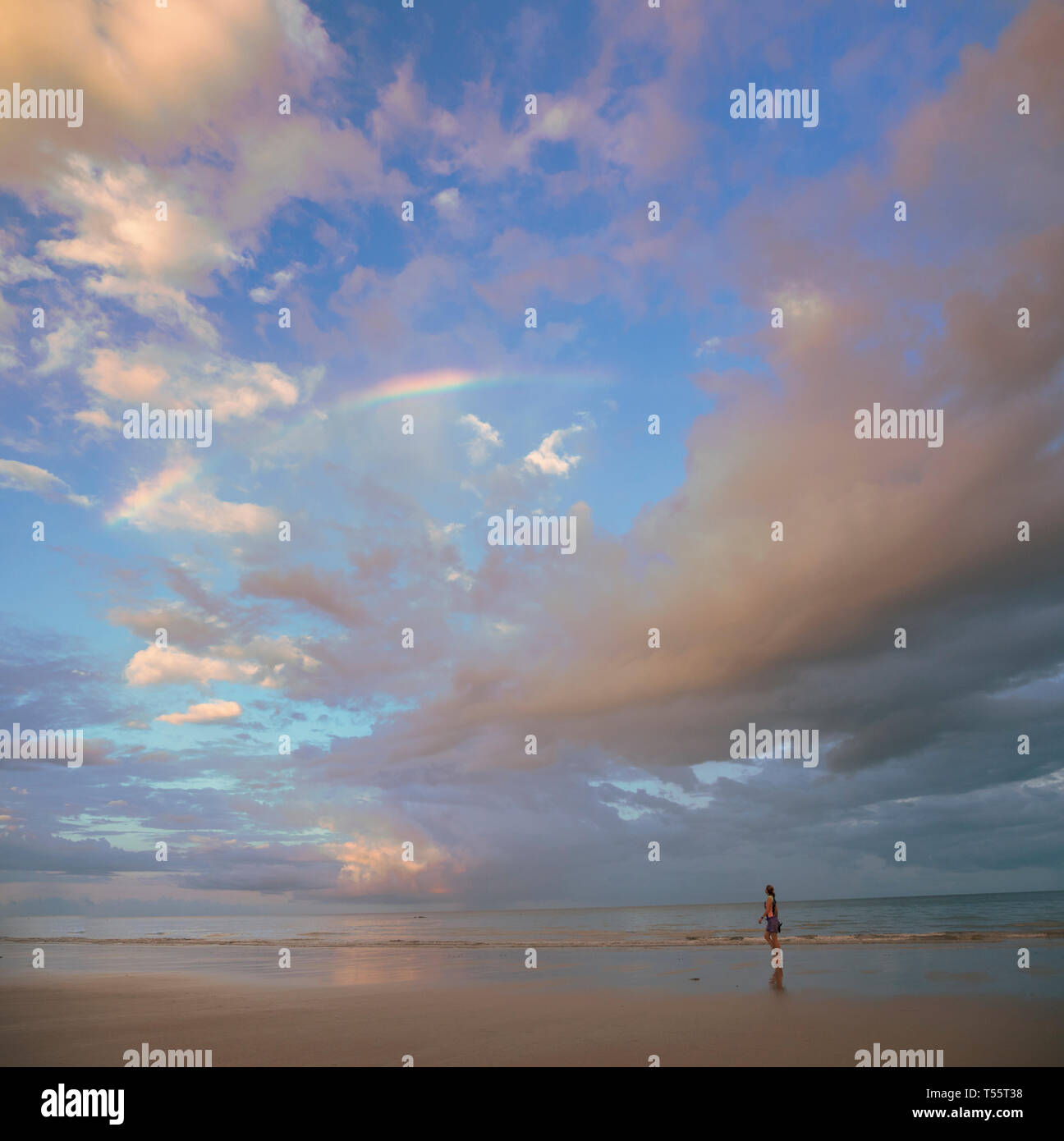 Cloudscape über Frau zu Fuß am Strand in Port Douglas, Australien Stockfoto