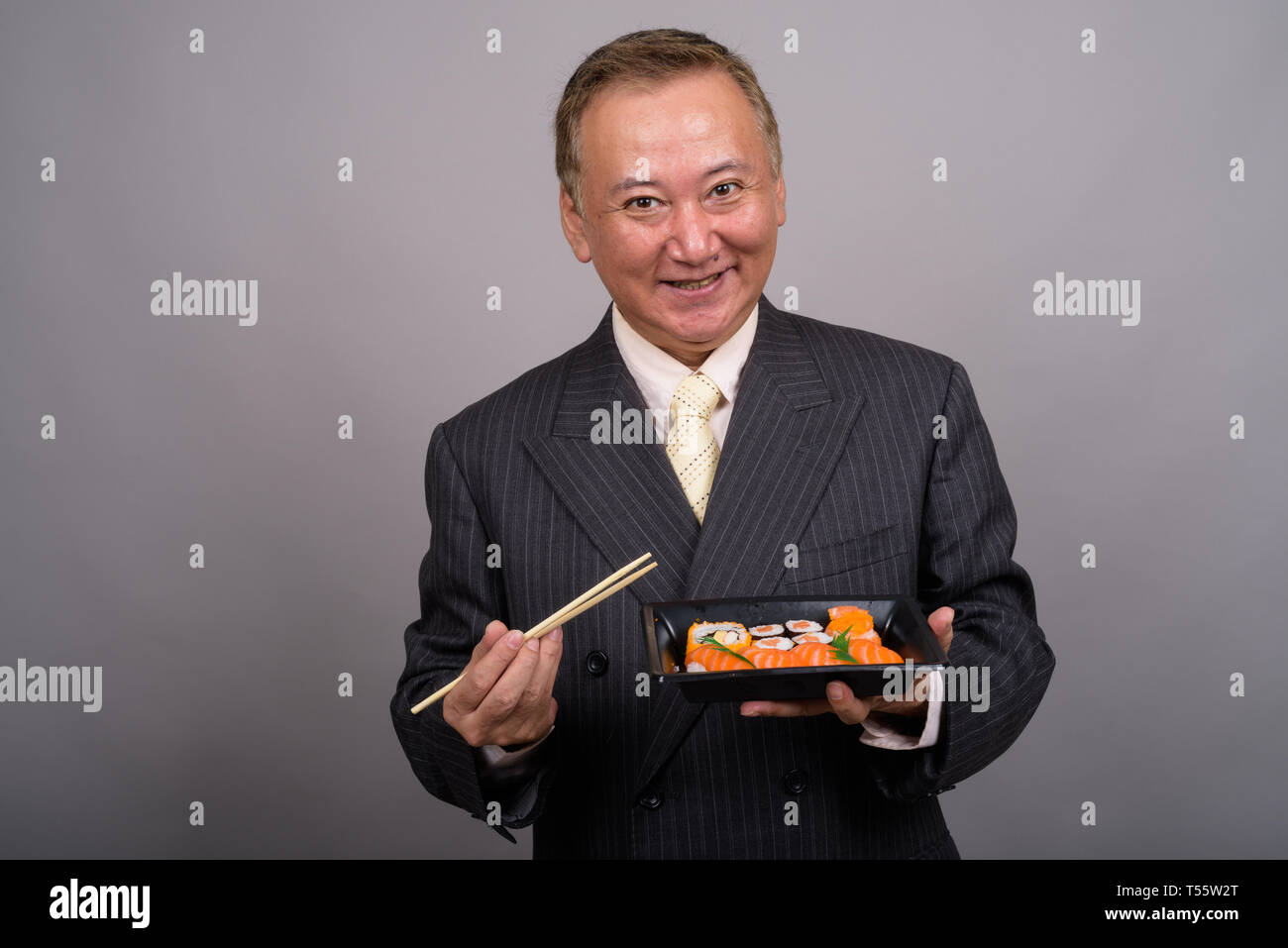 Portrait von Reifen asiatische Geschäftsmann gegen grauer Hintergrund Stockfoto