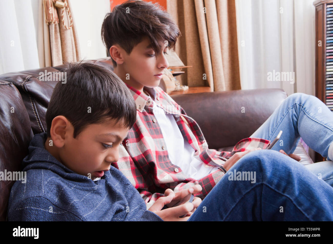 Brüder aus Smartphones auf dem Sofa Stockfoto