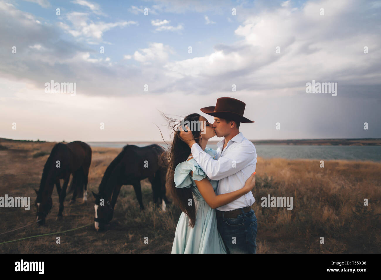 Junges Paar Küssen in Feld von Pferden Stockfoto