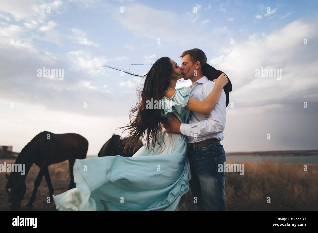 Junges Paar Küssen in Feld von Pferden Stockfoto