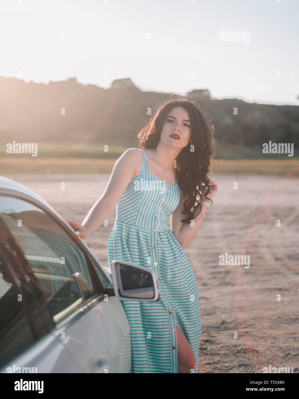 Junge Frau mit gestreiftem Kleid mit dem Auto Stockfoto
