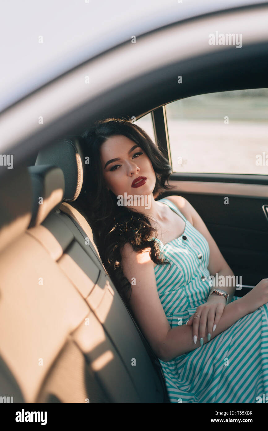 Junge Frau mit gestreiftem Kleid im Auto sitzen Stockfoto