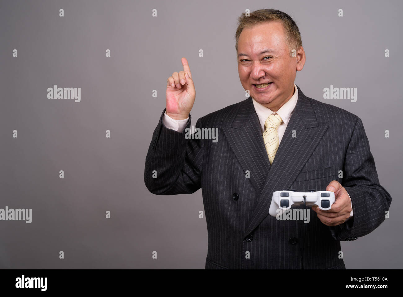 Portrait von Reifen asiatische Geschäftsmann gegen grauer Hintergrund Stockfoto