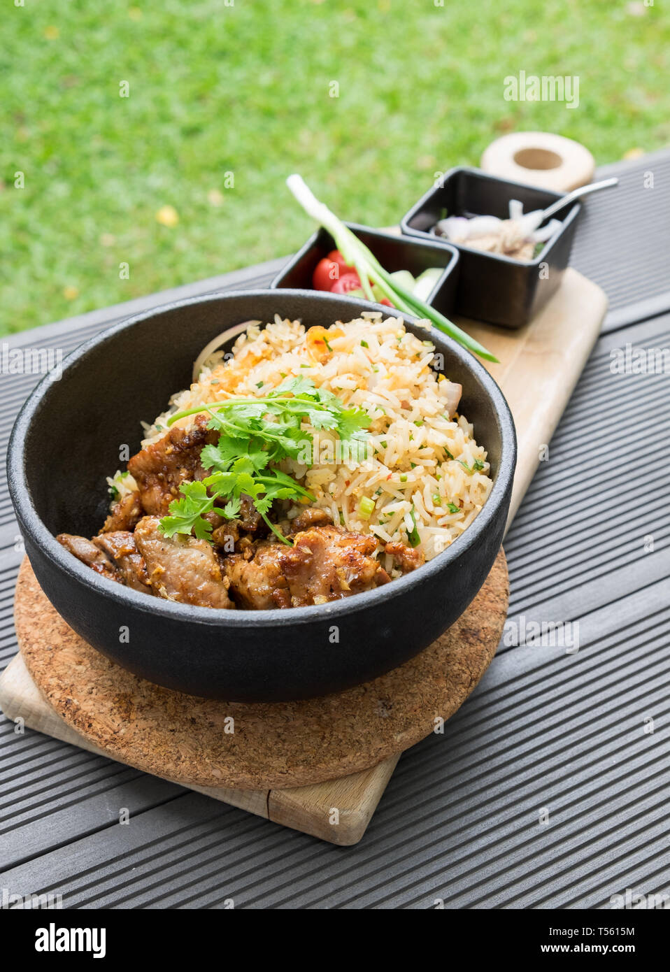 Gebratenes Schweinefleisch mit Knoblauch Gemüse mit Sauce würzig und sour Thai Essen lecker in schwarz Platte auf Holz- fach Stockfoto