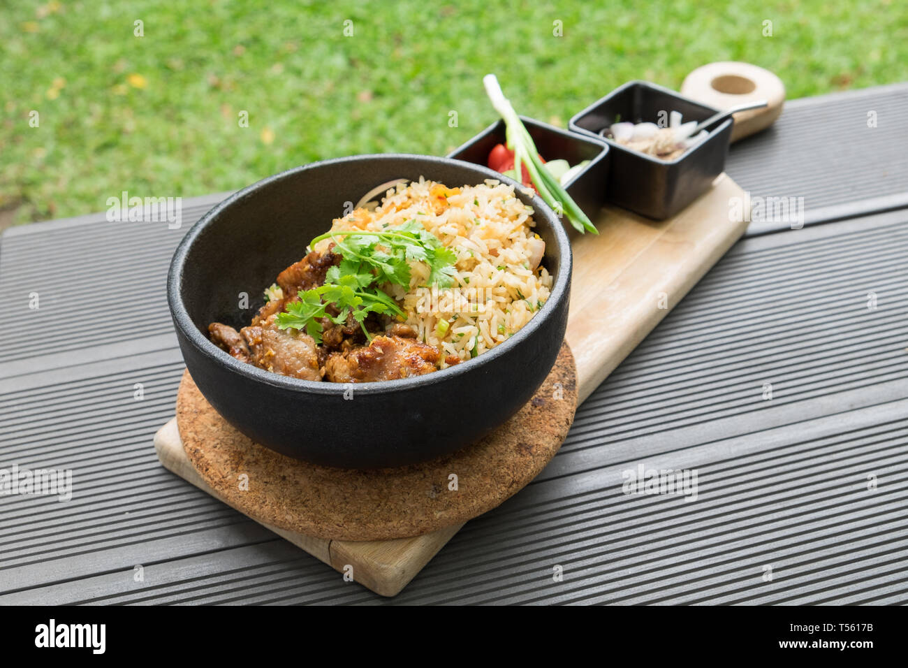 Gebratenes Schweinefleisch mit Knoblauch Gemüse mit Sauce würzig und sour Thai Essen lecker in schwarz Platte auf Holz- fach Stockfoto
