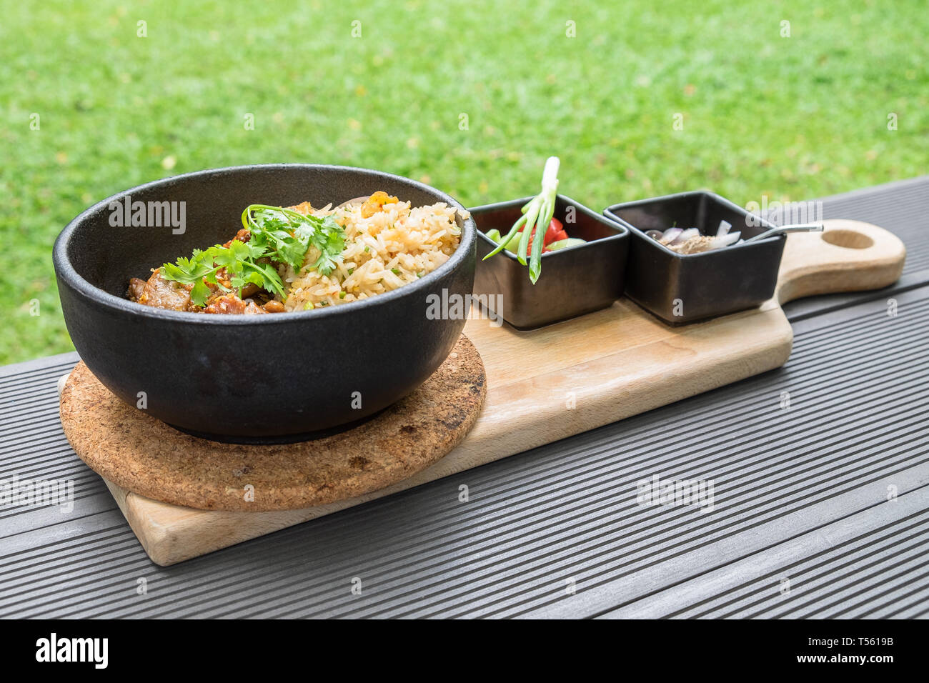 Gebratenes Schweinefleisch mit Knoblauch Gemüse mit Sauce würzig und sour Thai Essen lecker in schwarz Platte auf Holz- fach Stockfoto