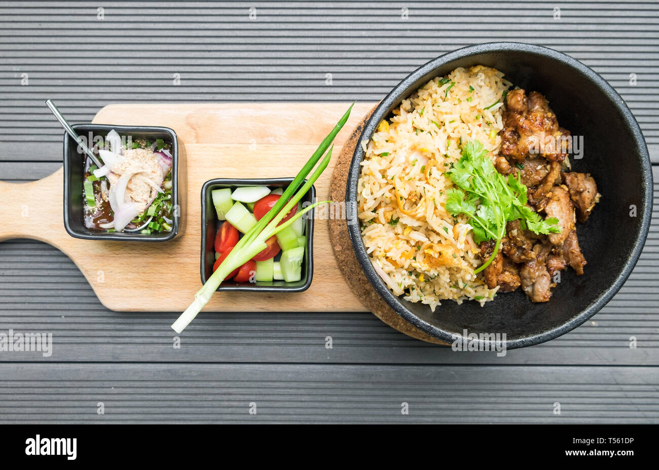 Gebratenes Schweinefleisch mit Knoblauch Gemüse mit Sauce würzig und sour Thai Essen lecker in schwarz Platte auf Holz- fach Stockfoto