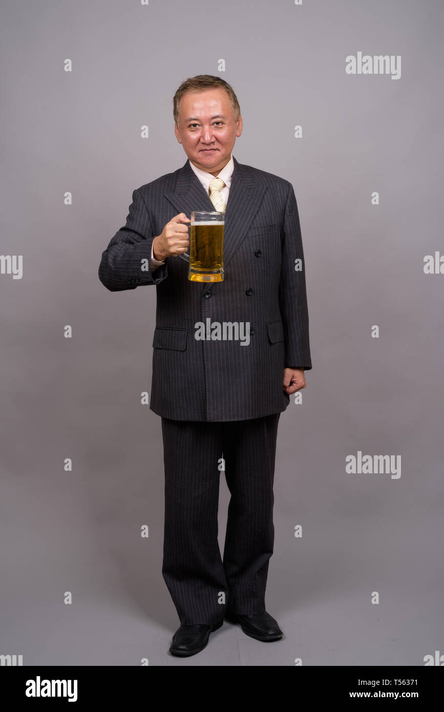 Portrait von Reifen asiatische Geschäftsmann gegen grauer Hintergrund Stockfoto