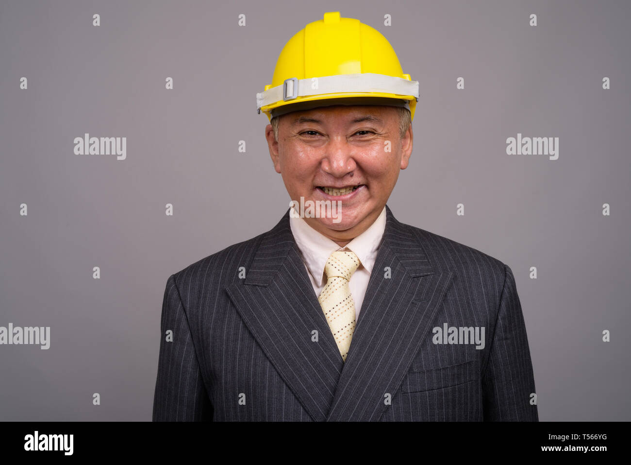 Reifen asiatischen Bau Unternehmer gegen grauer Hintergrund Stockfoto