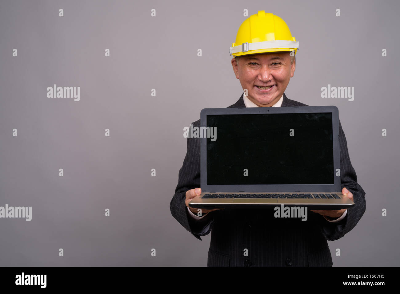Reifen asiatischen Bau Unternehmer gegen grauer Hintergrund Stockfoto