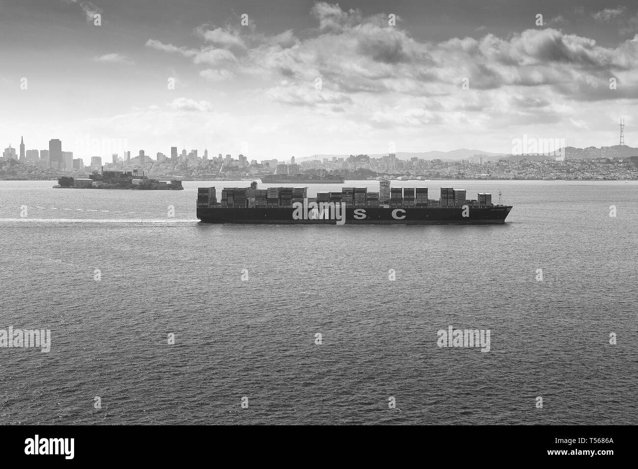 Moody Black and White Photo of the Container Ship, MSC ARIANE, dampfend durch San Francisco Bay, Alcatraz links und hinten. USA. Stockfoto