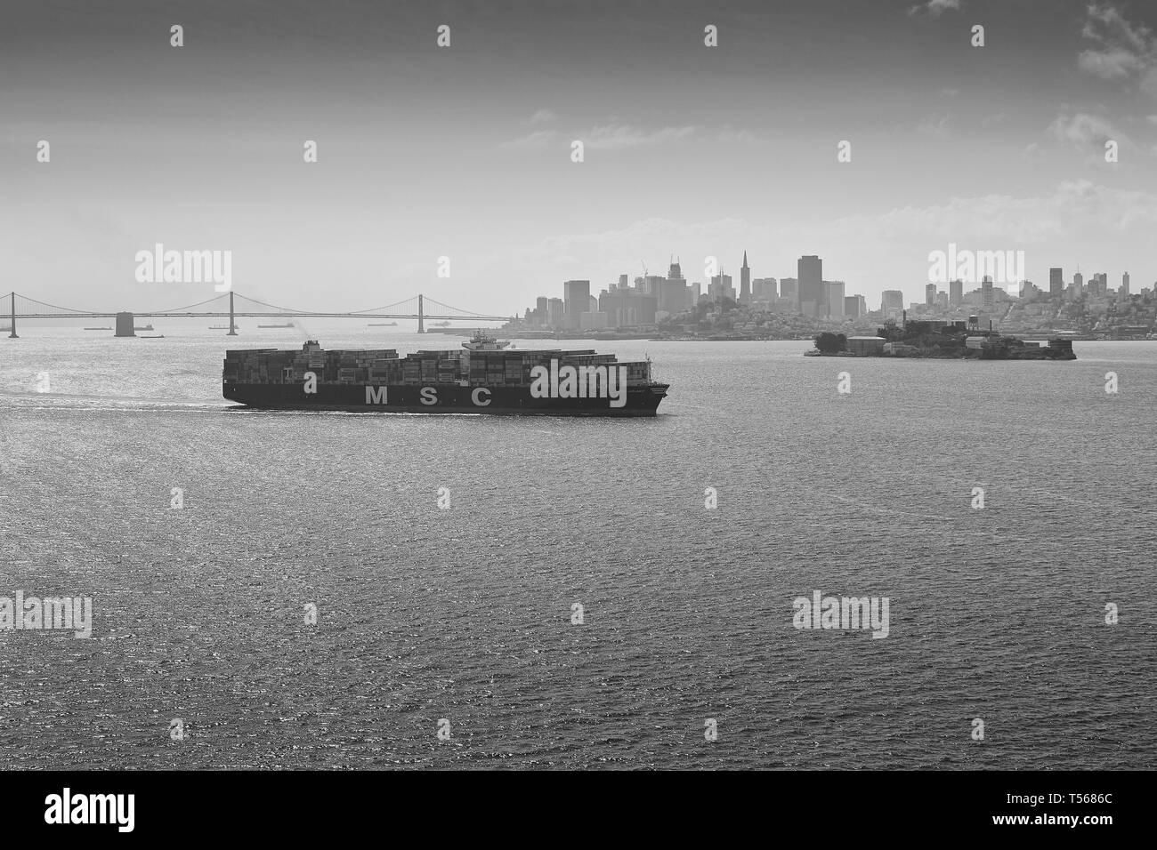 Schwarz-weiß-Foto von Mediterranean Shipping Company Containerschiff, MSC ARIANE, dampfend durch die San Francisco Bay, San Francisco Skyline dahinter. Stockfoto