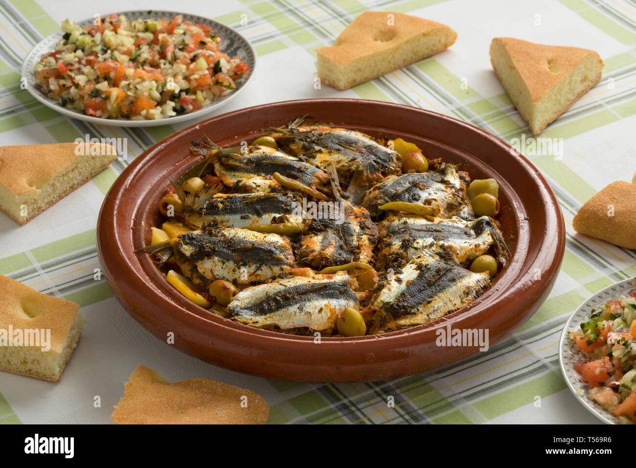 Traditionelle marokkanische Tajine mit Gefüllte Sardinen, Salat und Brot auf dem Tisch für das Abendessen Stockfoto