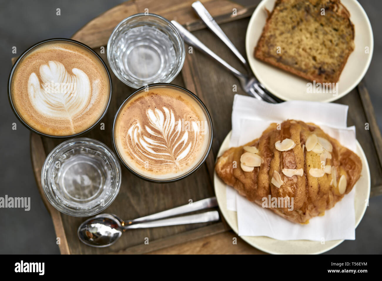 Milch Kaffee mit Croissant, Brot und Wasser auf hölzernen Tisch Stockfoto