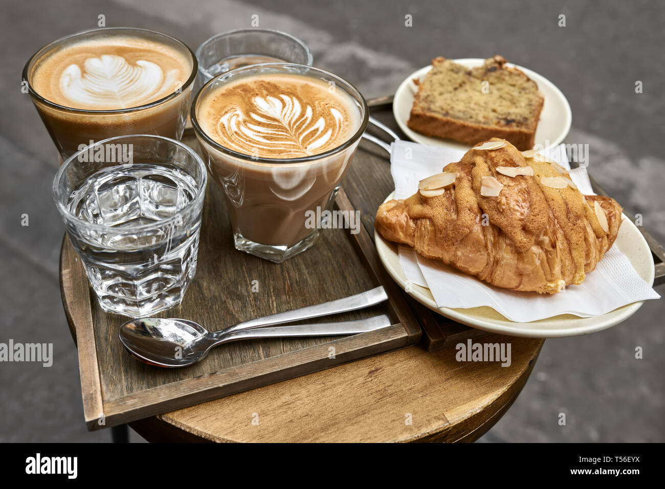 Milch Kaffee mit Croissant, Brot und Wasser auf hölzernen Tisch Stockfoto