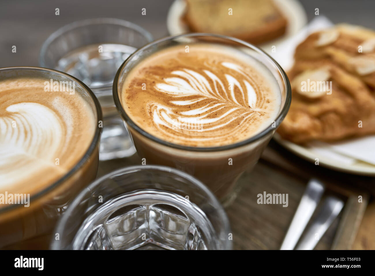 Milch Kaffee mit Croissant, Brot und Wasser auf hölzernen Tisch Stockfoto