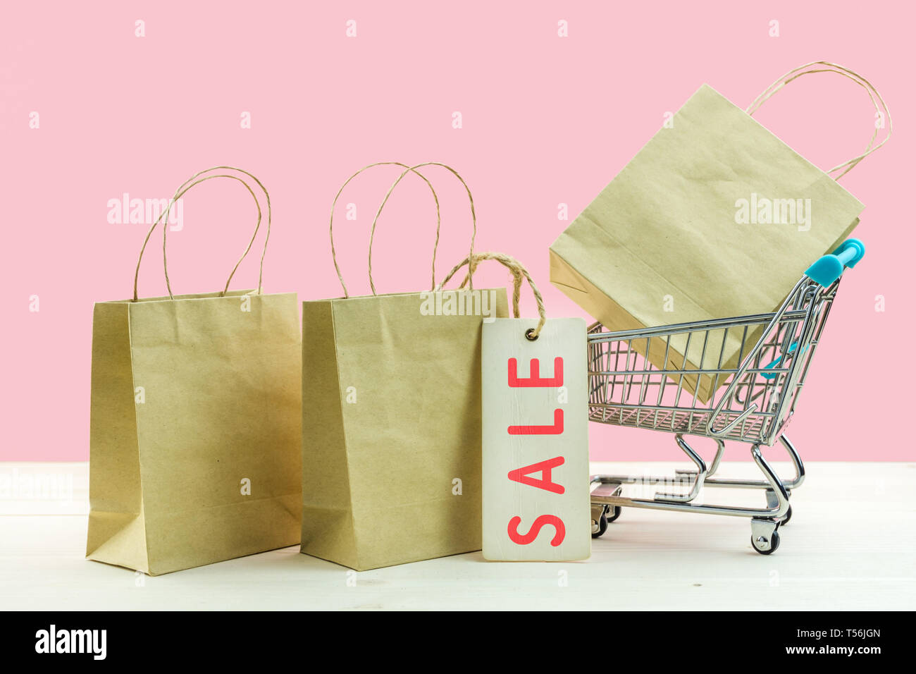 Trolley Warenkorb und Papier Einkaufstüten auf rosa Hintergrund. Kreative Idee für Online-shopping, Summer Sale, Supermarkt, Werbeaktion und Schwarz Fr. Stockfoto