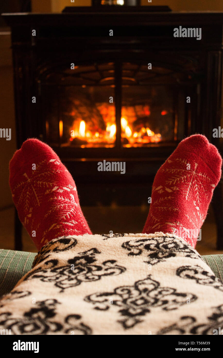 Warmen gemütlichen roten Socken vor einem warmen Kamin im Haus und eine Decke Stockfoto