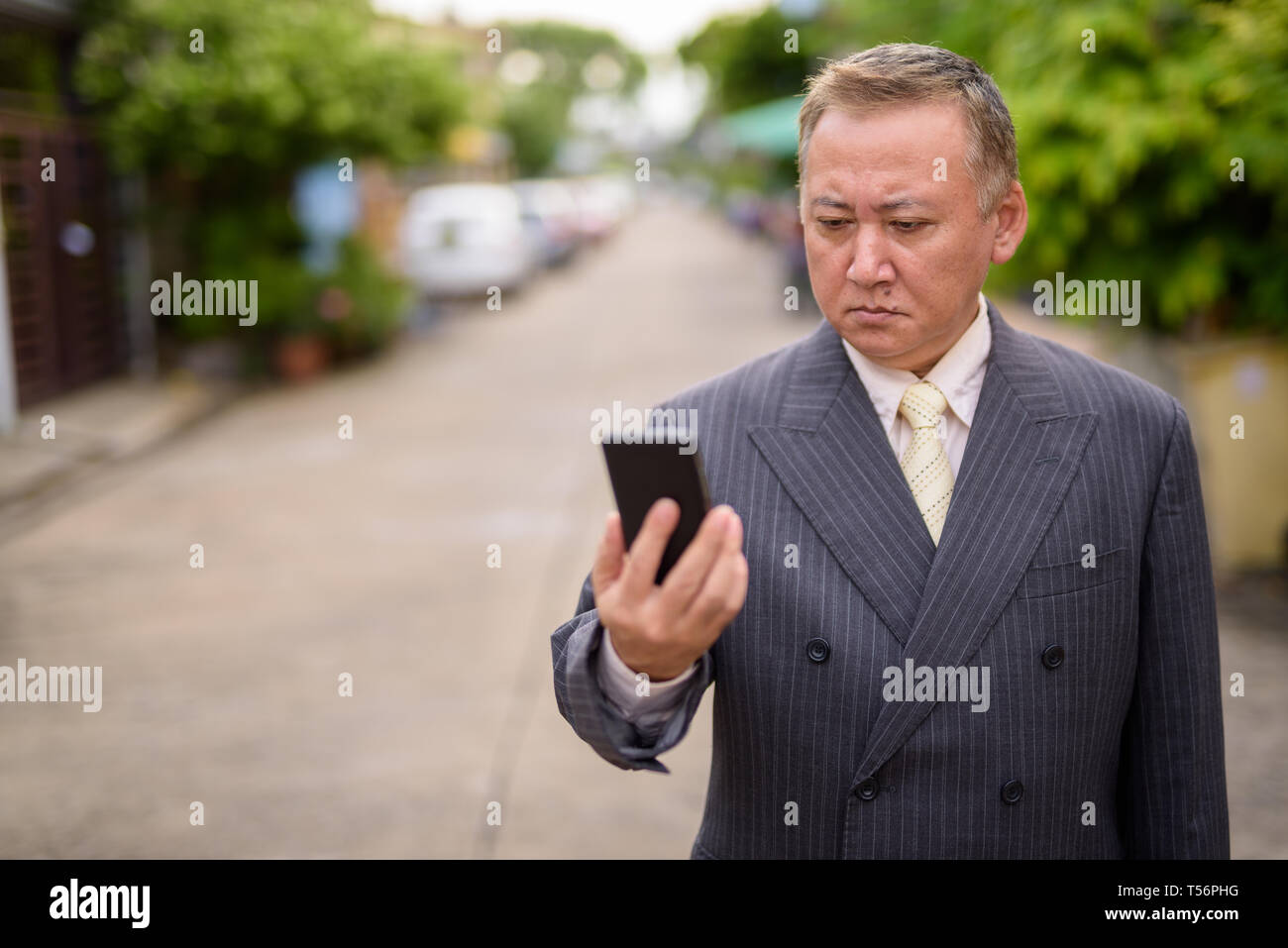 Reifen asiatische Geschäftsmann mit Mobiltelefon in den Straßen übertreffen Stockfoto