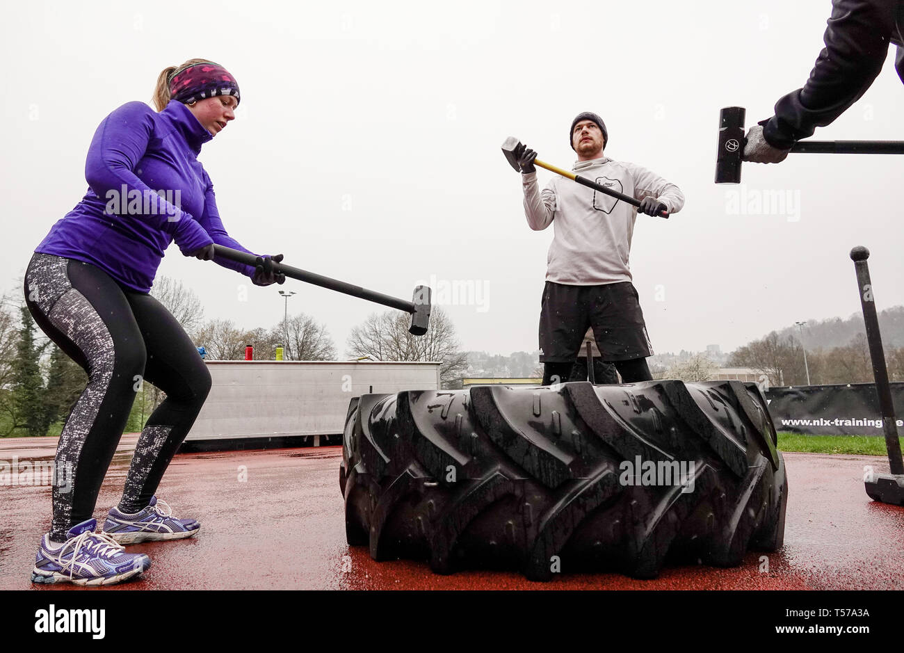 10 April 2019, Baden-Württemberg, Tübingen: Deike Lüdtke (l) und Jurij  Keßler schlug einen LKW-Reifen mit Hämmern auf einem Sportplatz. Athleten  aus Tübingen sind Schulungen für eine Charity-veranstaltung am 27. April,  während der