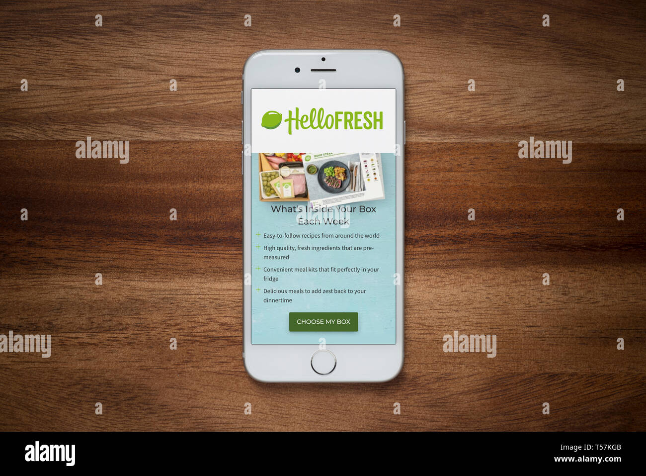 Ein iPhone mit den Hallo frische Website beruht auf einem einfachen Holztisch (nur redaktionelle Nutzung). Stockfoto