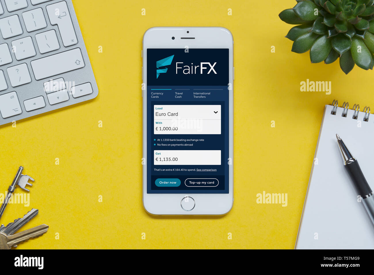 Ein iPhone zeigt die FairFX website ruht auf einem gelben Hintergrund Tabelle mit einer Tastatur, Tasten, Notepad und Anlage (nur redaktionelle Nutzung). Stockfoto