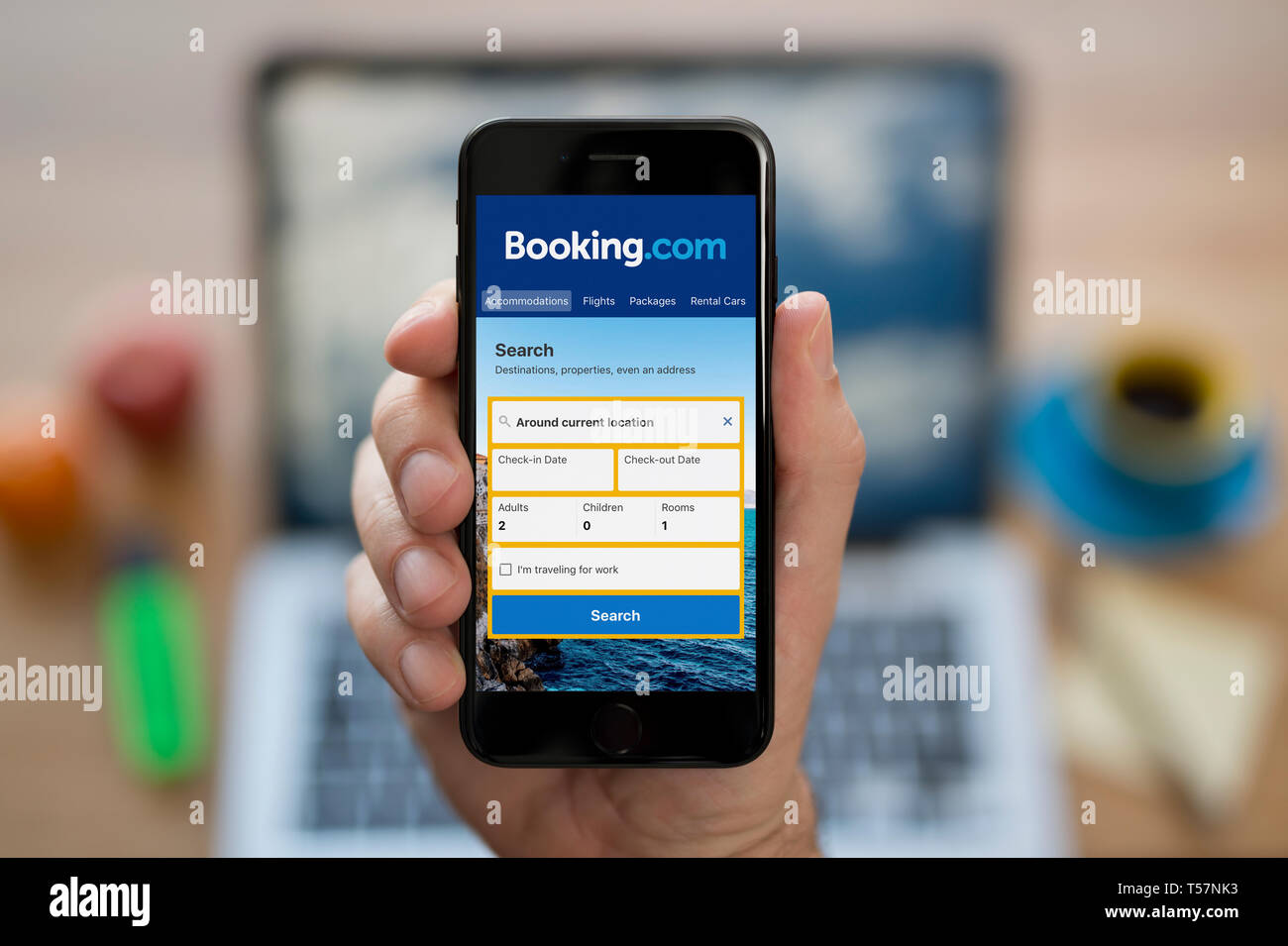 Ein Mann schaut auf seinem iPhone zeigt die Booking.com Logo (nur redaktionelle Nutzung). Stockfoto