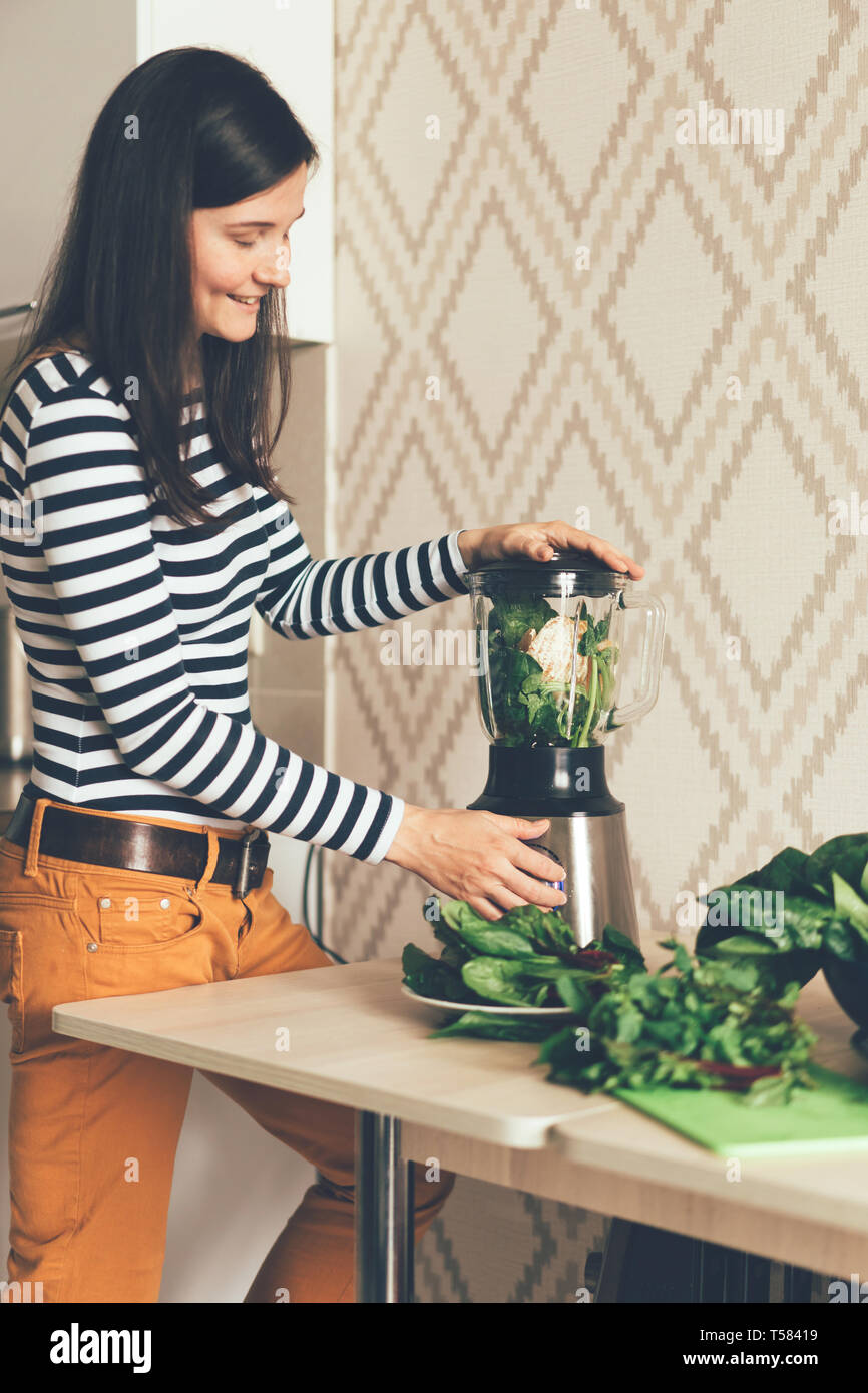 Pretty Woman stilvoll gekleidet, grüne Smoothies in der Küche Stockfoto
