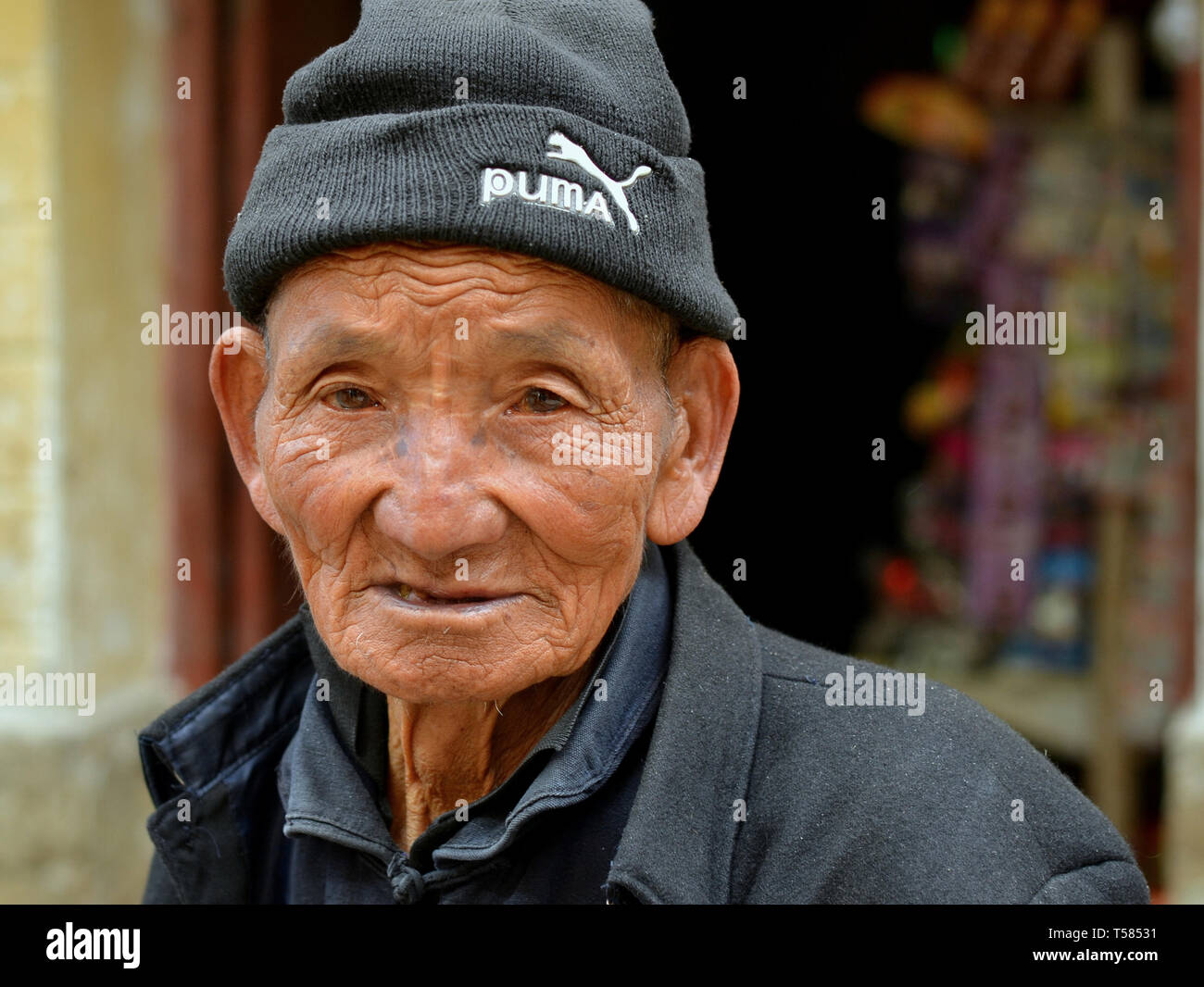 Alte Han-chinesische Farm hand mit lebte - Gesicht eine Wollene Skull Cap trägt und posiert für die Kamera. Stockfoto