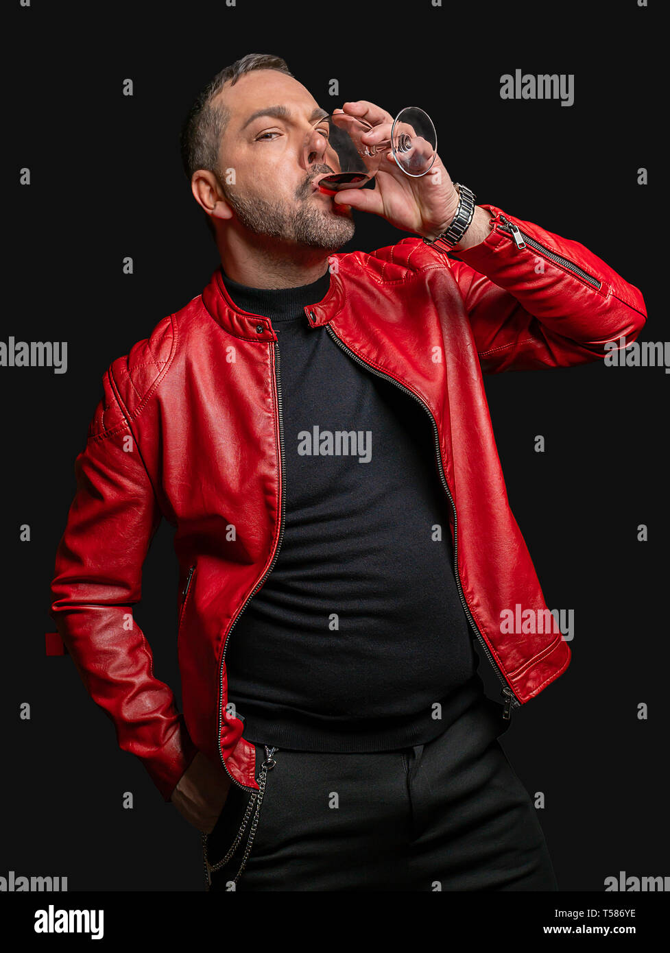 Ein Mann in der stilvollen Kleidung gegen eine isolierte Hintergrund Getränke aus einem Glas Wein. Stockfoto