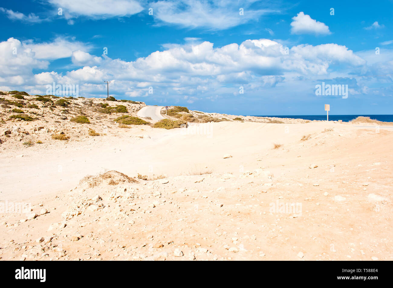Bild von rauhem Kalkstein Küste in der Nähe von Kap Greco, Zypern. Viele weiße Wolken am Himmel, kargen orange sandigen Hügel, Weite. Warmer Tag im Herbst Stockfoto