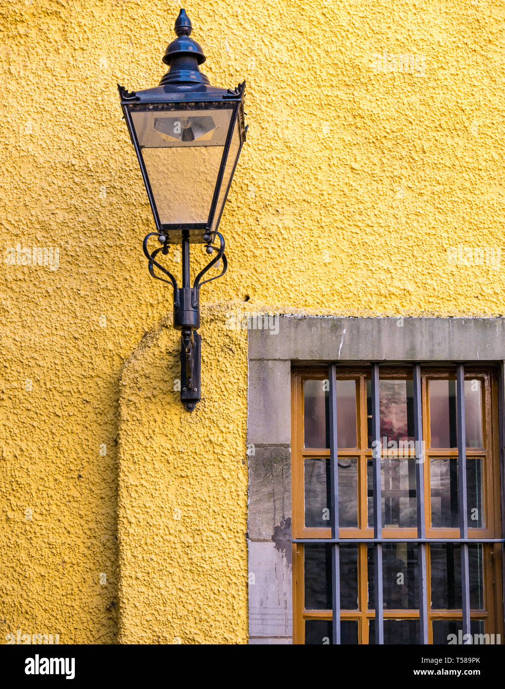 Alte Lampe auf Gelb lime gewaschen Wand im Innenhof des Museums von Edinburgh, der Royal Mile, Edinburgh, Schottland, Großbritannien Stockfoto