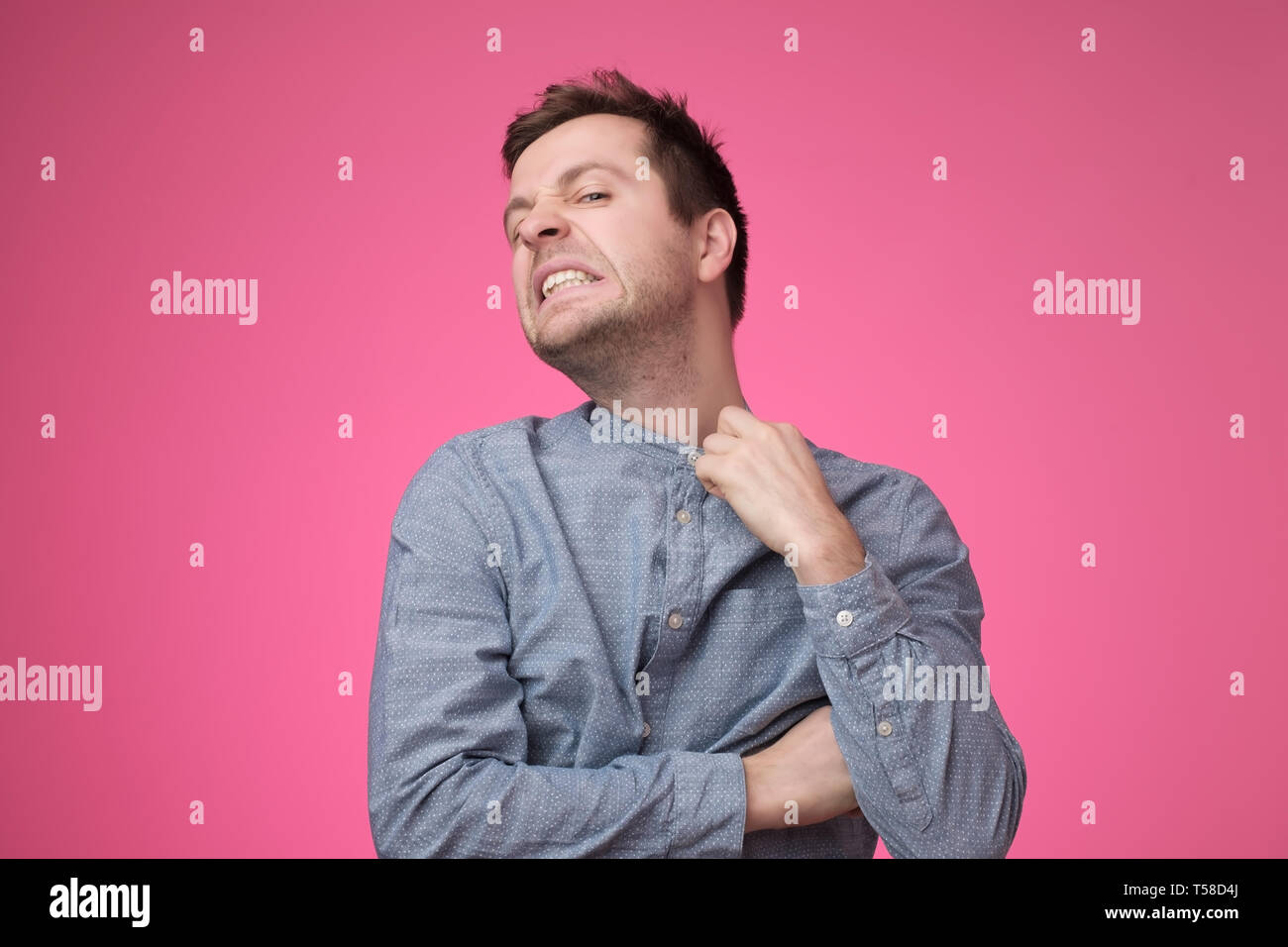 Stirnrunzelnd junge Unternehmer erdrosseln versuchen, weg von seinem Hemd zu setzen. Stockfoto