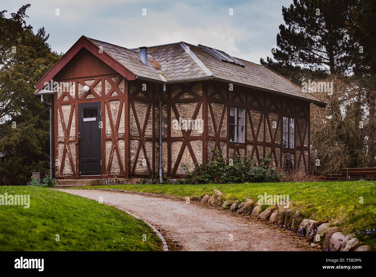 Das Haus, ein kleines Haus auf dem Hügel, umgeben von Grün, eine rote Erde Weg führt zum Eingang Stockfoto