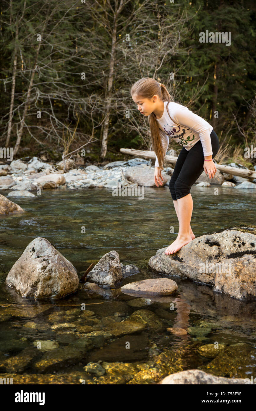 Olallie State Park, in der Nähe von North Bend, Washington, USA. Neun Jahre altes Mädchen zögern und denken sie zweimal vor dem hüpfen auf den nächsten Felsen im Norden f Stockfoto