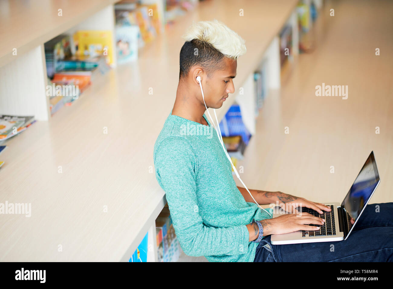 Moderne Kerl arbeiten an Artikel in der Bibliothek Stockfoto