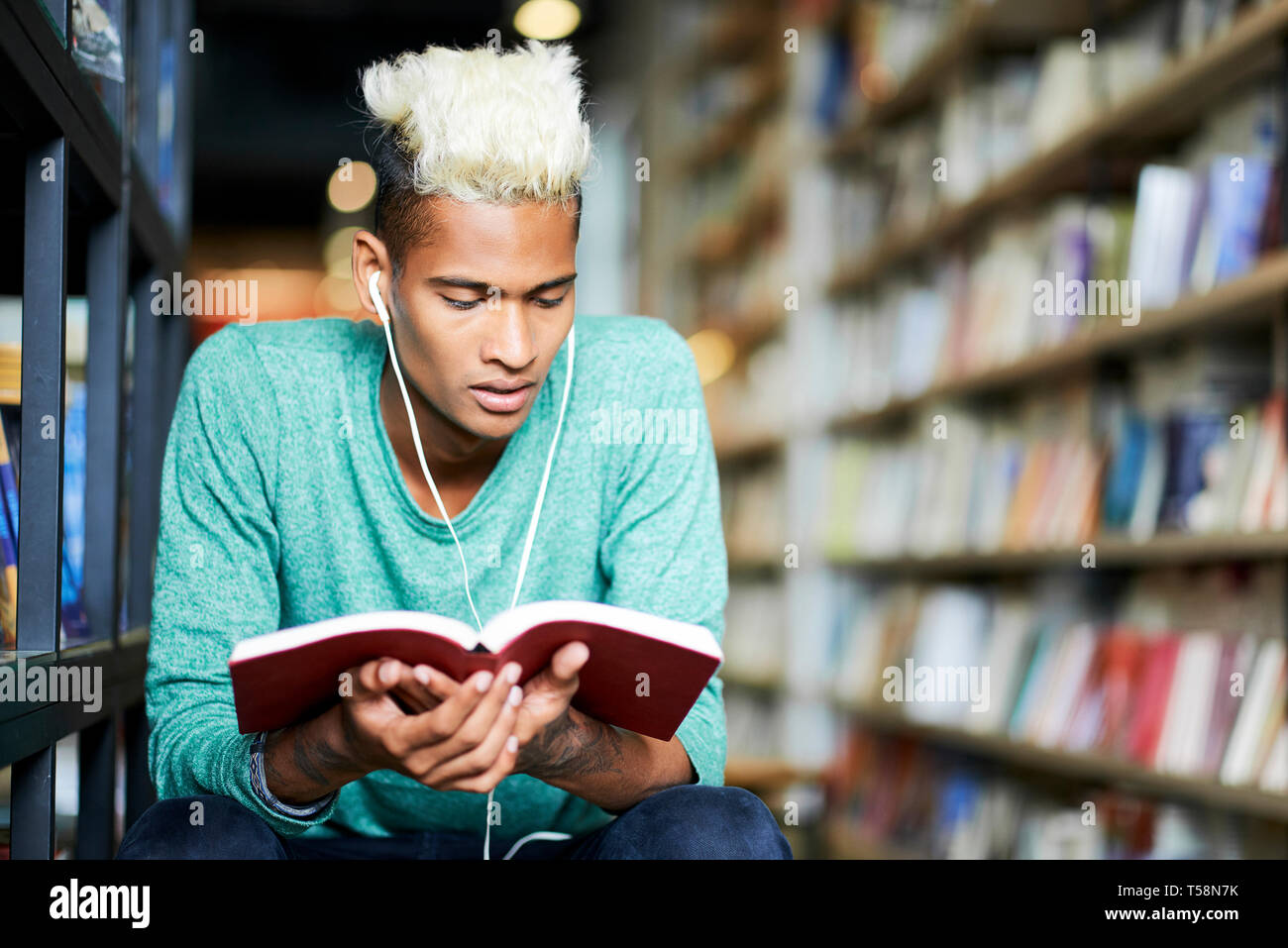 Nachdenklich Student der Ohrhörer Buch lesen Stockfoto