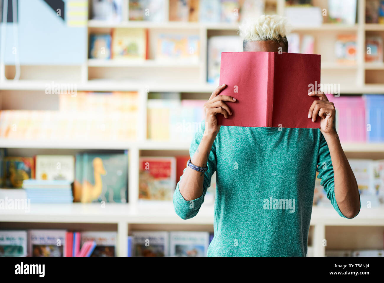 Student ausblenden Gesicht hinter Buch Stockfoto