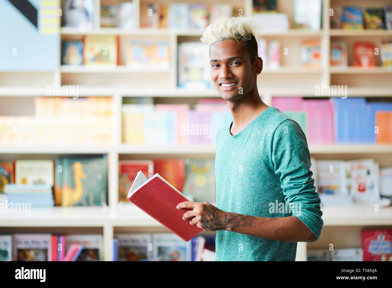 Hübscher junger Student in der Bibliothek Stockfoto