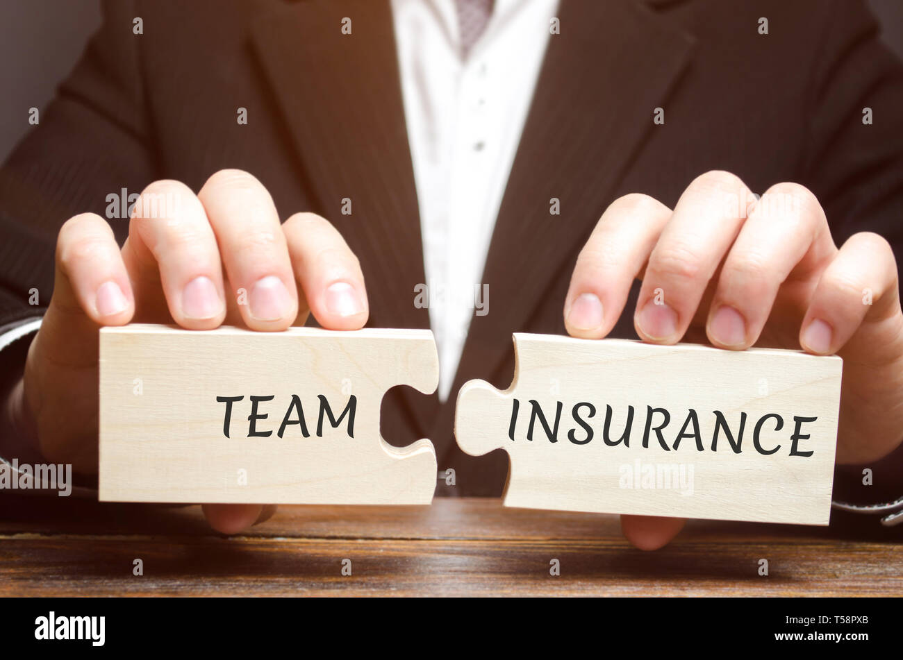 Geschäftsmann sammelt Rätsel mit den Worten Team Versicherung. Sicherheit und Sicherheit in einem Business Team. Fürsorge für die Mitarbeiter. Eine Verantwortung. Mitarbeiter con Stockfoto