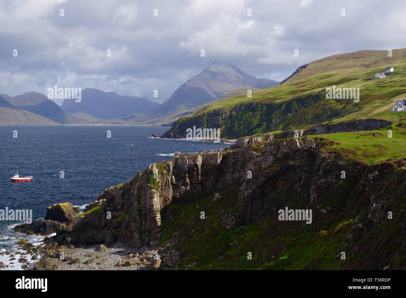 Kleine rote Fischerboot im Loch Scavaig in Elgol, durch die schroffen Cullin Hills. Isle of Skye, Schottland, Großbritannien. Stockfoto