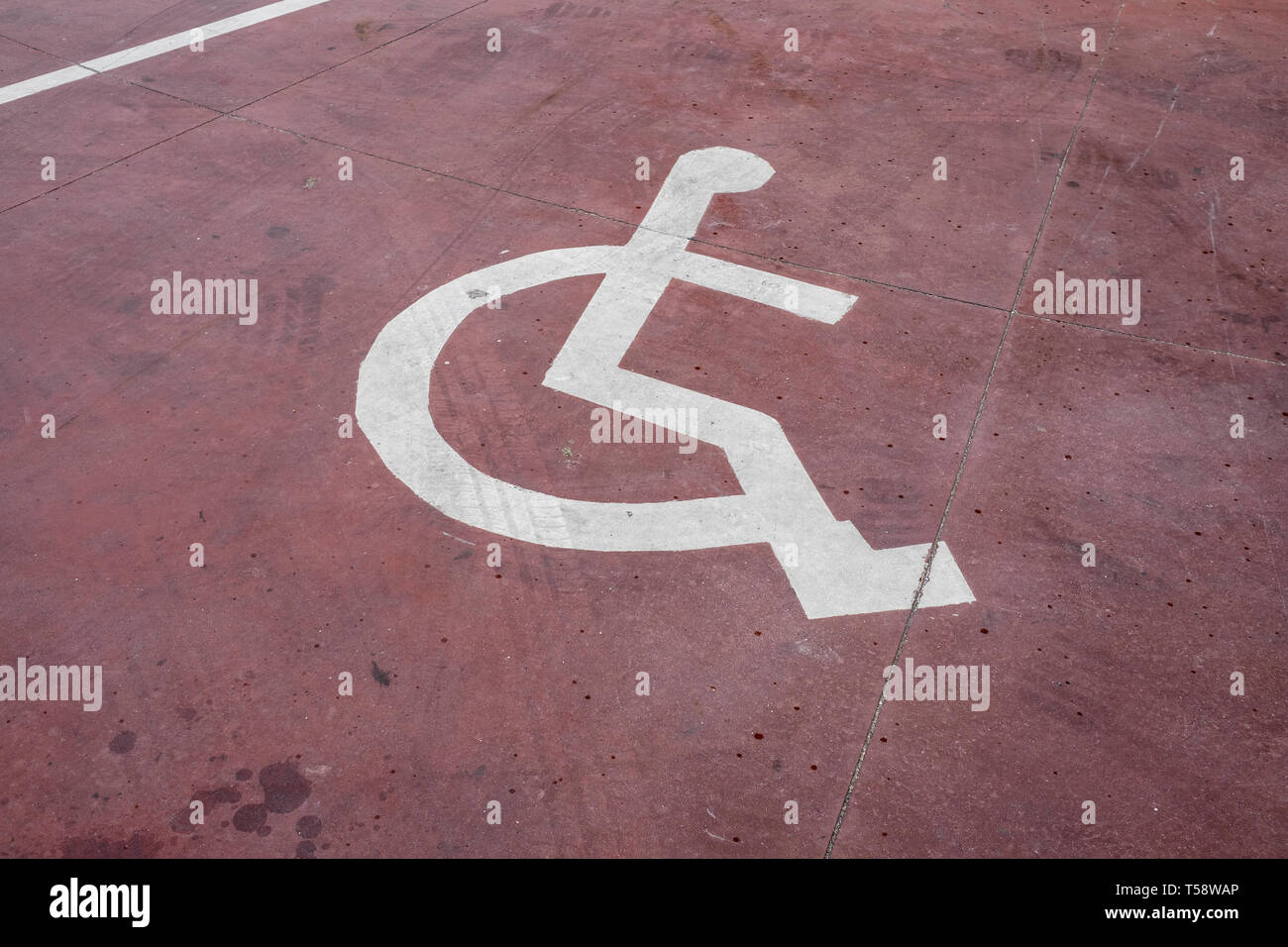 Behinderte weisse Zeichen auf rotem Boden lackiert Stockfoto