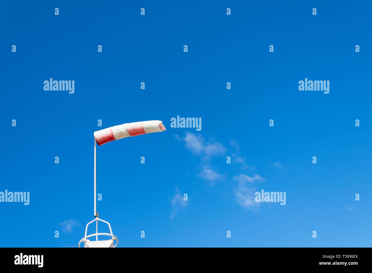 Rot Weiß Windsack angibt, von wo der Wind kommt mit einem blauen Hintergrund und ein Paar weiße Wolken Stockfoto