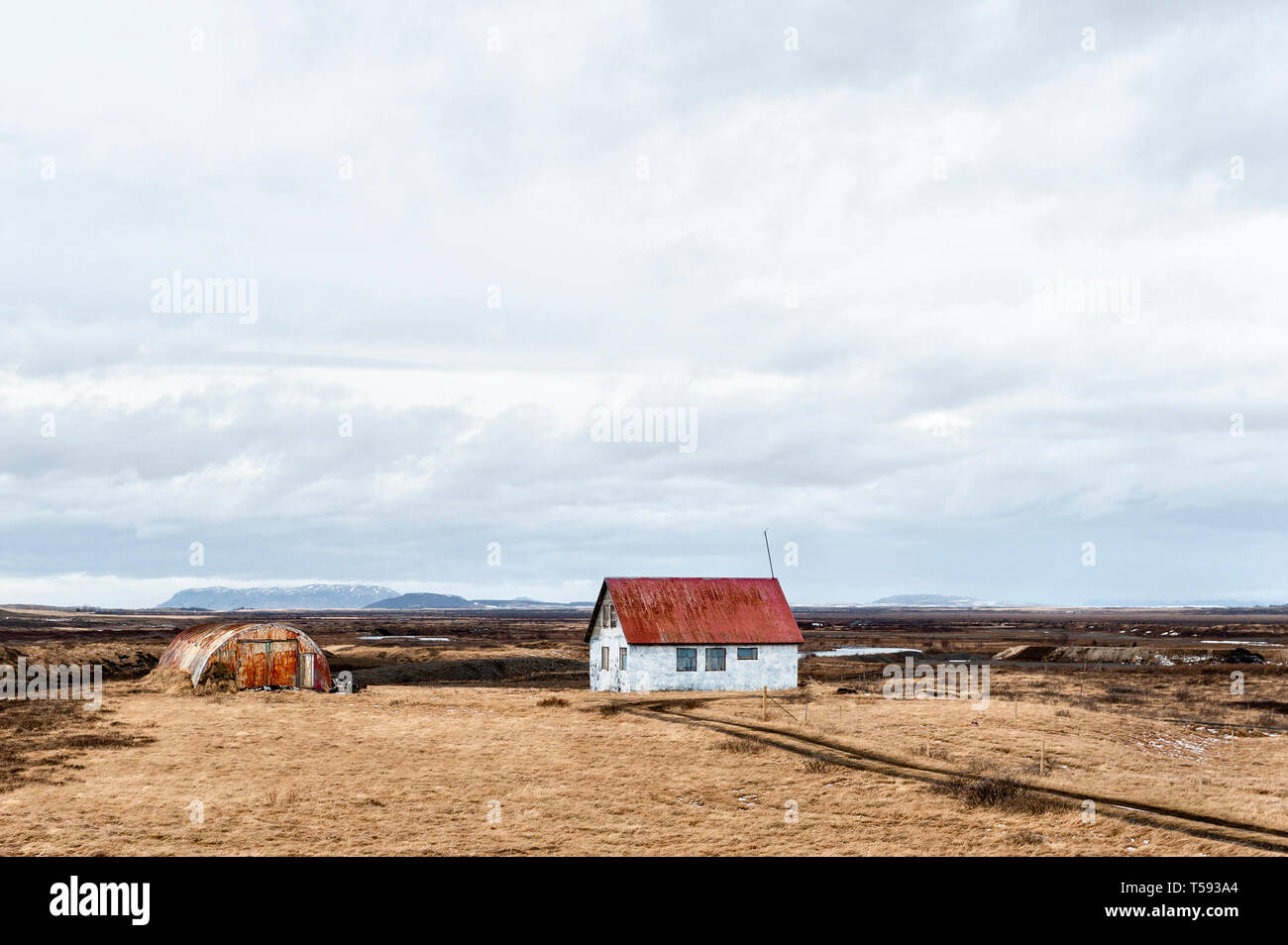 Einsames Bauernhaus und Wellblechscheune in der leeren Landschaft von SW Island (Ende März) Stockfoto