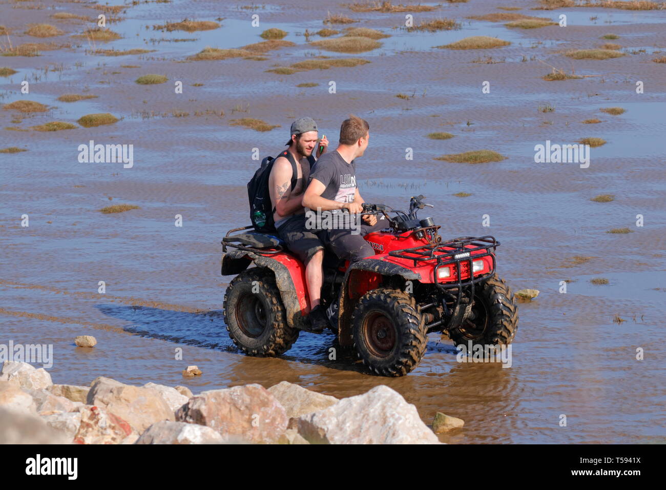 Männer, die mit dem Quad an einem Strand in Grange fahren - über Sand Stockfoto