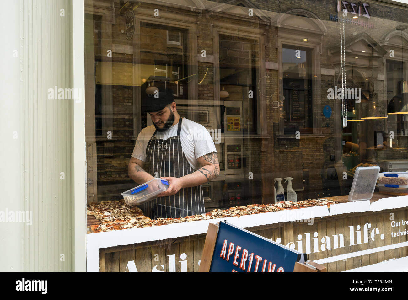 Koch hinzufügen Topping zu Pizza im Aromi cafe Benet Street Cambridge 2019 Stockfoto