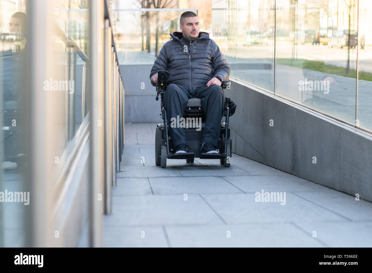 Mann in einem elektrischen Rollstuhl über eine Rampe Stockfoto